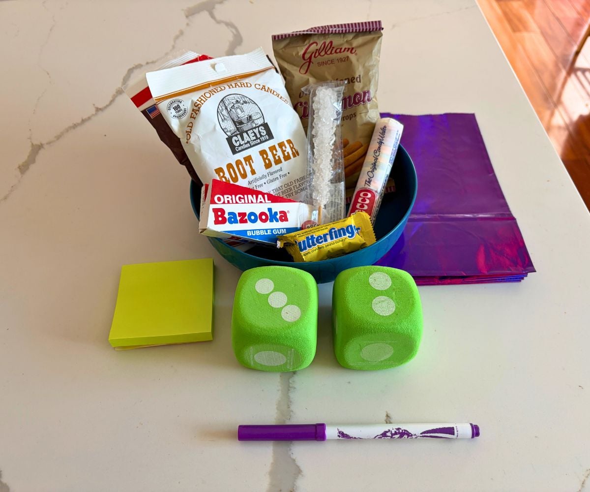 two large green dice, Post-It Notes, purple bags, and a bowl full of candies from different parts of history