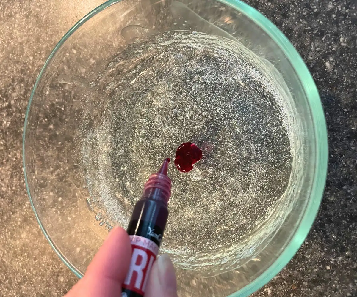 woman adding 20 drops of dye to melted soap base