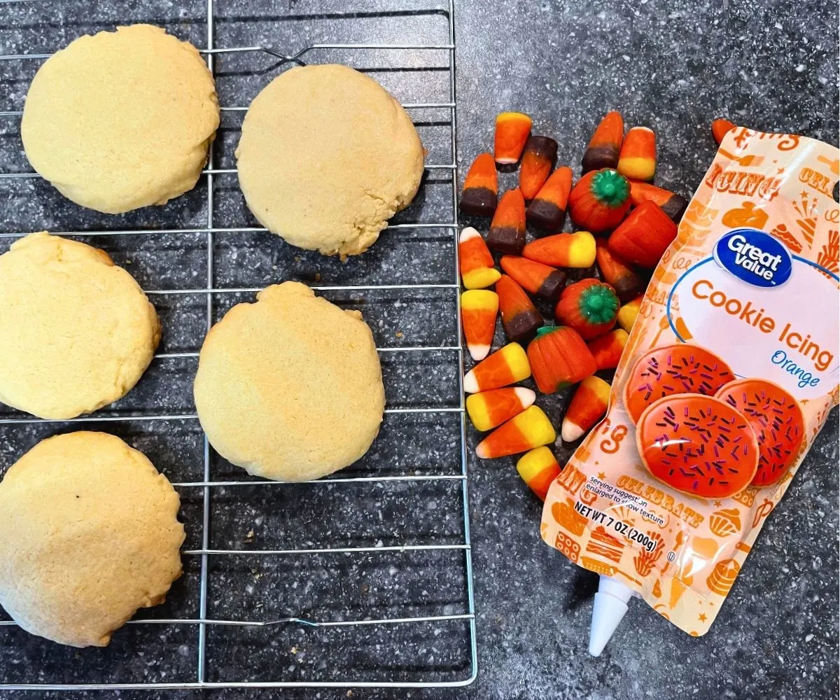 sugar cookies on rack next to candy corns and orange cookie icing