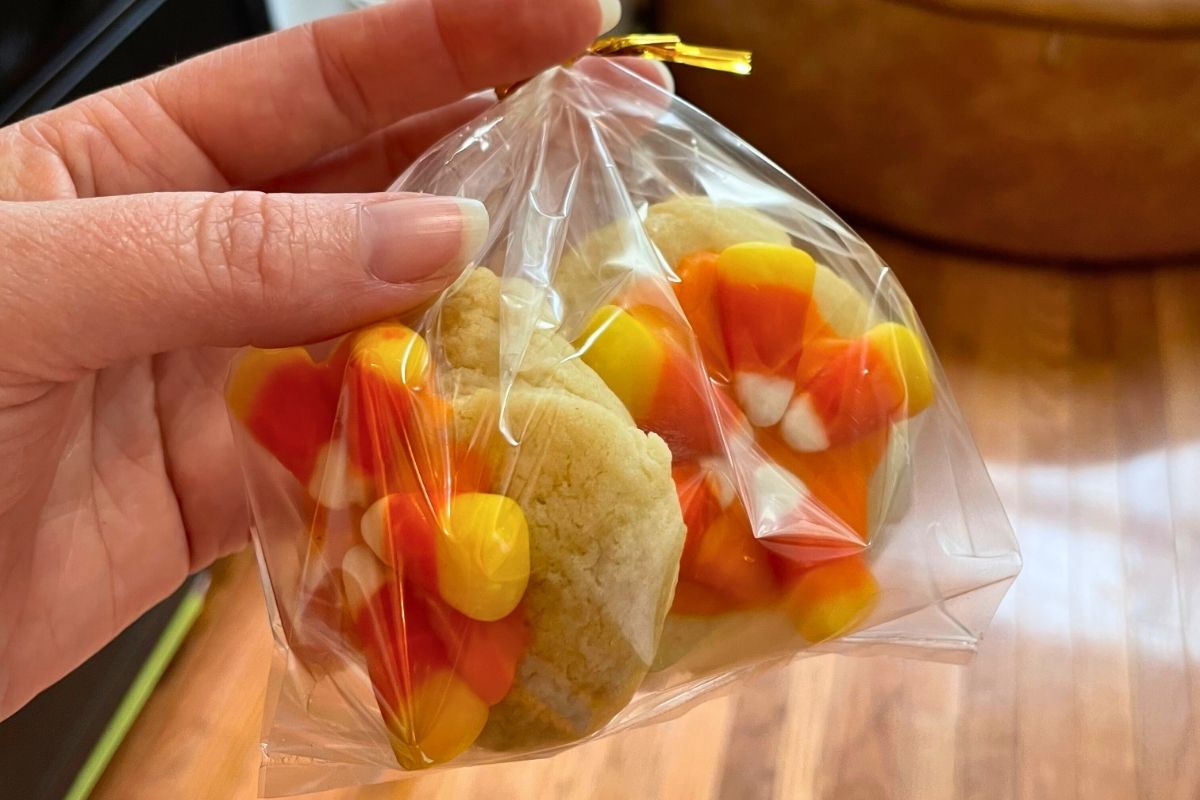 woman holding two candy corn coated cookies in plastic bag
