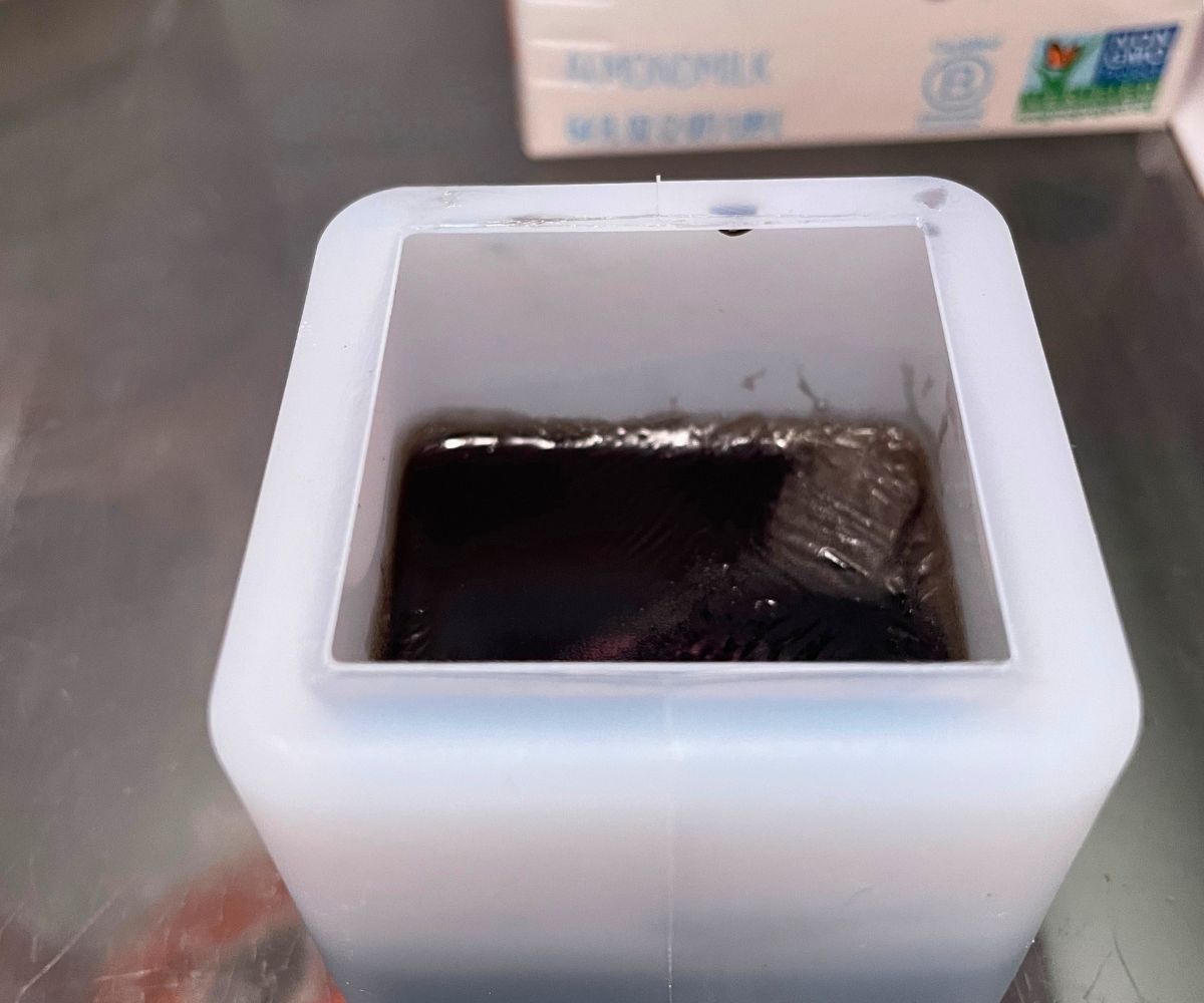cube mold half filled with black soap