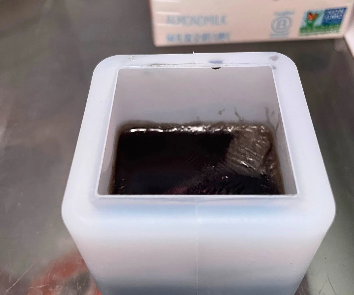 cube mold half filled with black soap