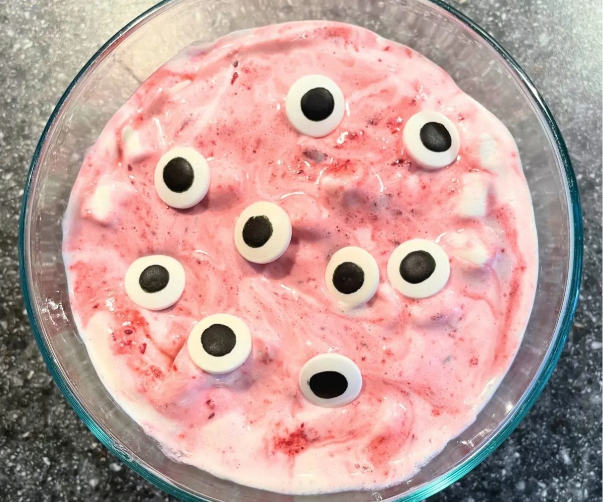 bowl of red streaked fluff with big googly eyes and mini marshmallows