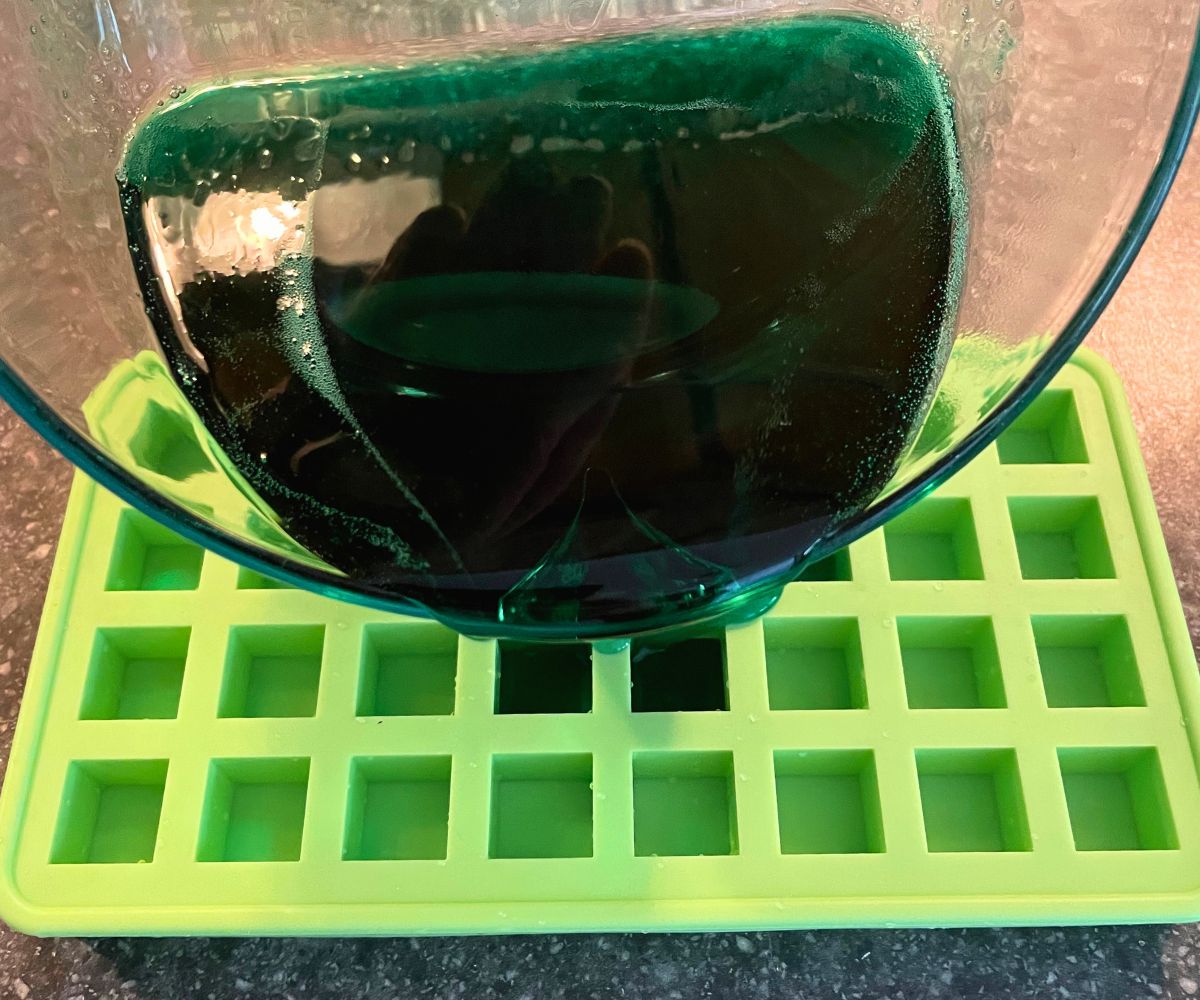 Woman pouring melted green soap into small cube container