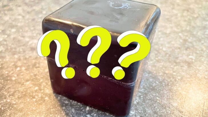 black cube of soap with three neon question marks over it