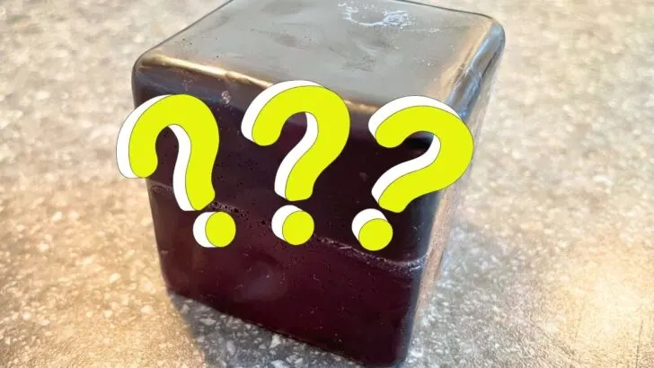 black cube of soap with three neon question marks over it