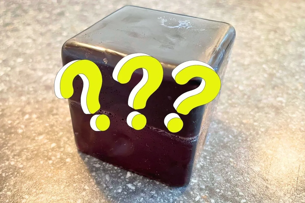 black cube of soap with three neon question marks over it