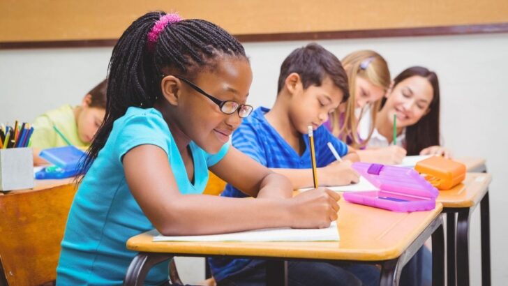 group of elementary school students at desk working on money project