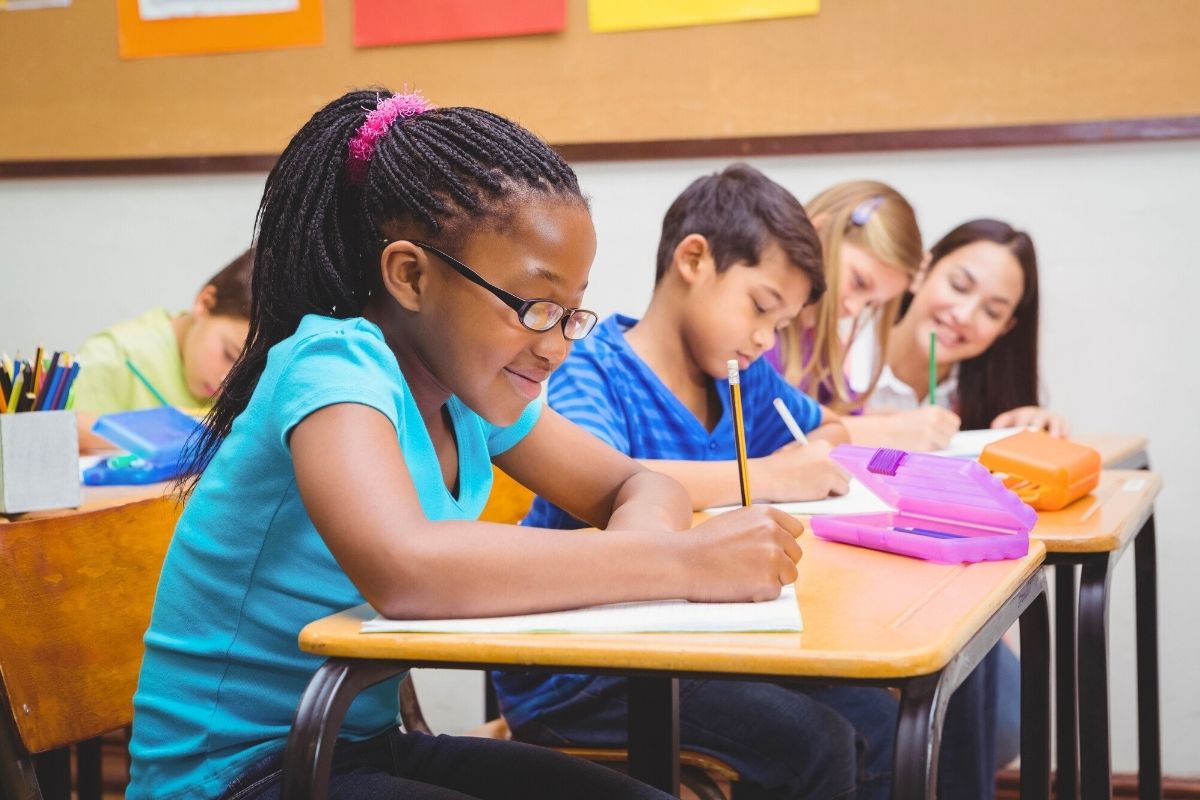 group of elementary school students at desk working on money project
