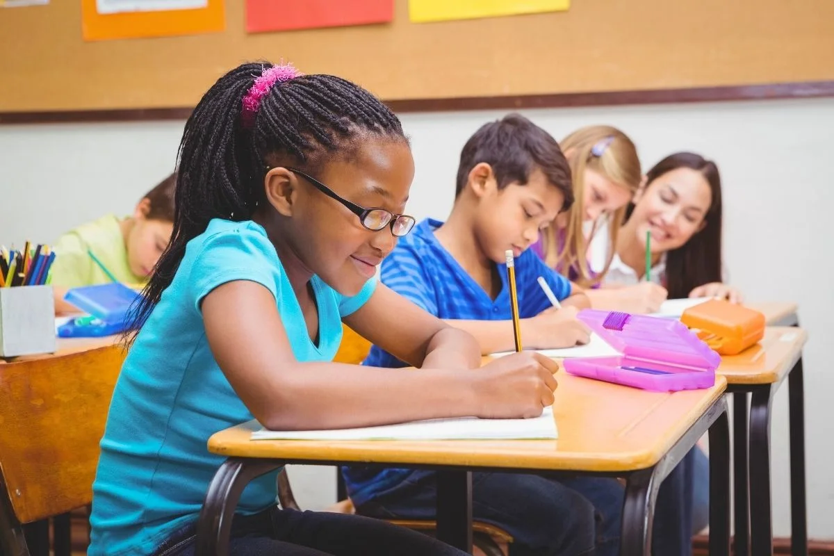 group of elementary school students at desk working on money project