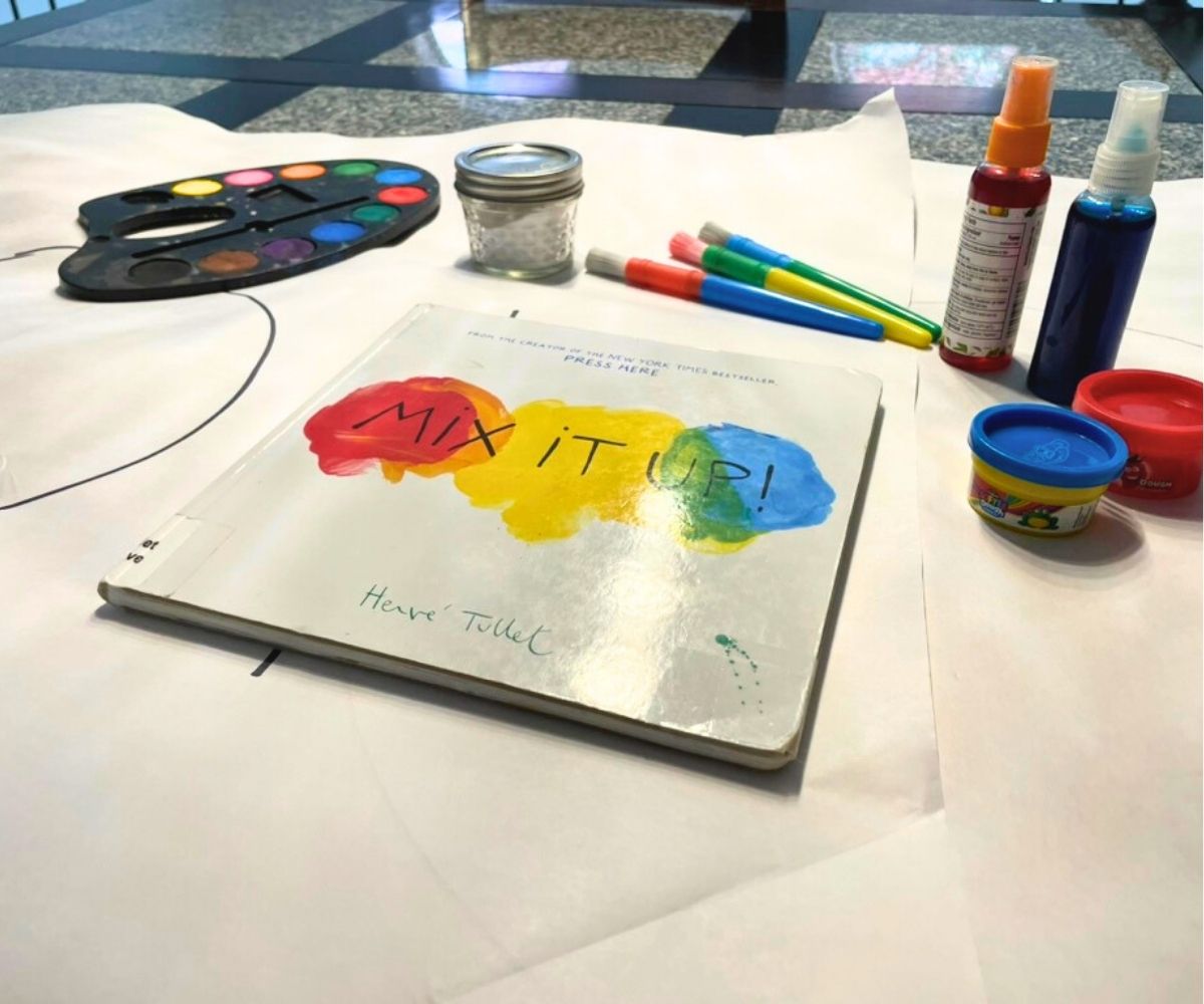 Mix It Up colorful book next to lots of color play things: paints, spray bottles, brushes, Play Doh, etc.