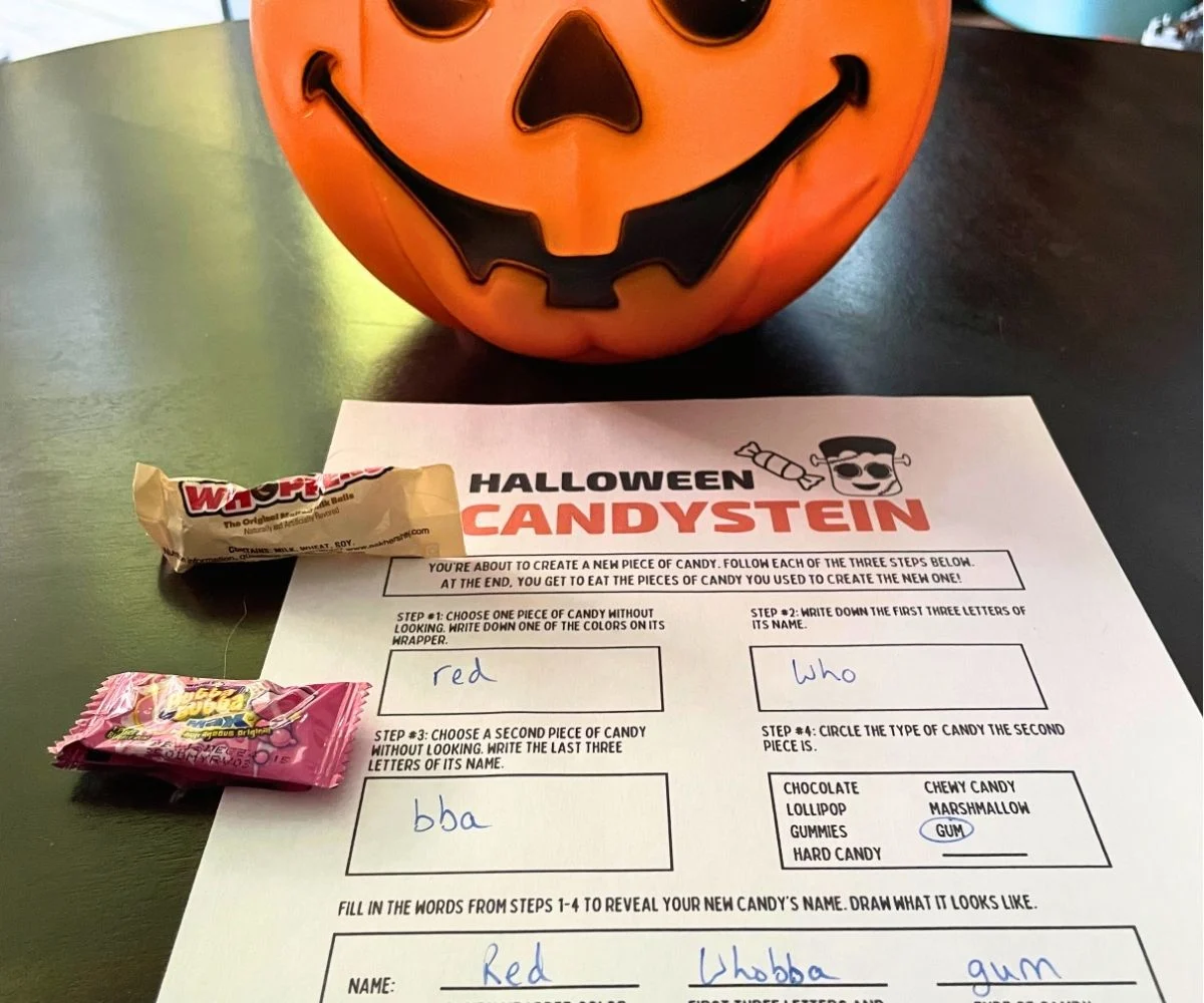 pumpkin pail of candy next to Halloween Candystein printable on dark table