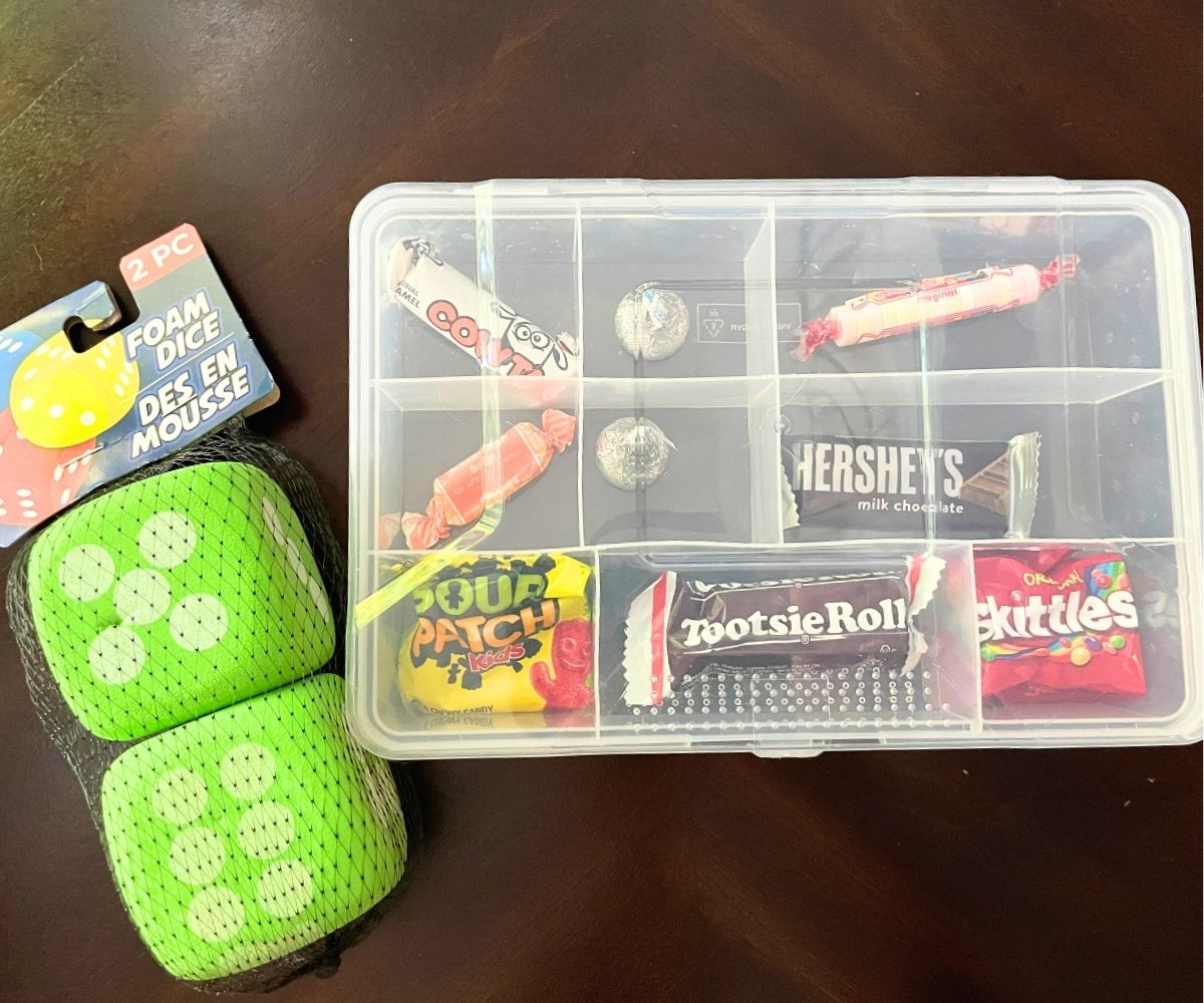 tacklebox filled with one piece of candy in each compartment next to funky green dice
