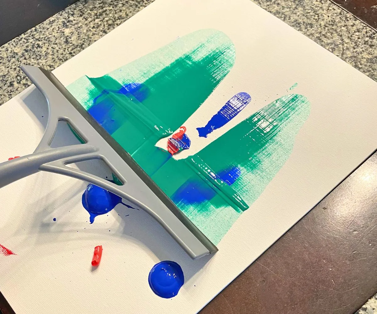 another canvas with 10-year-old using squeegee to slide paint across