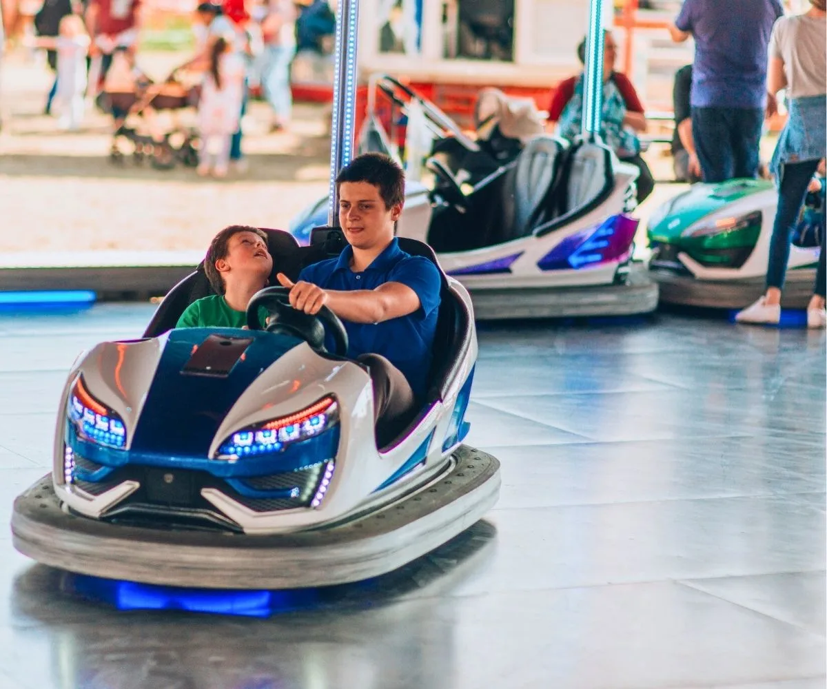 teen boy with kid in his bumper car at an amusement park