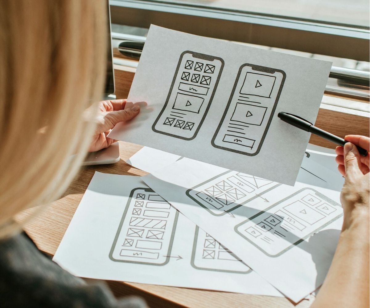 girl teen looking at different sheets of paper with a mobile app laid out on it