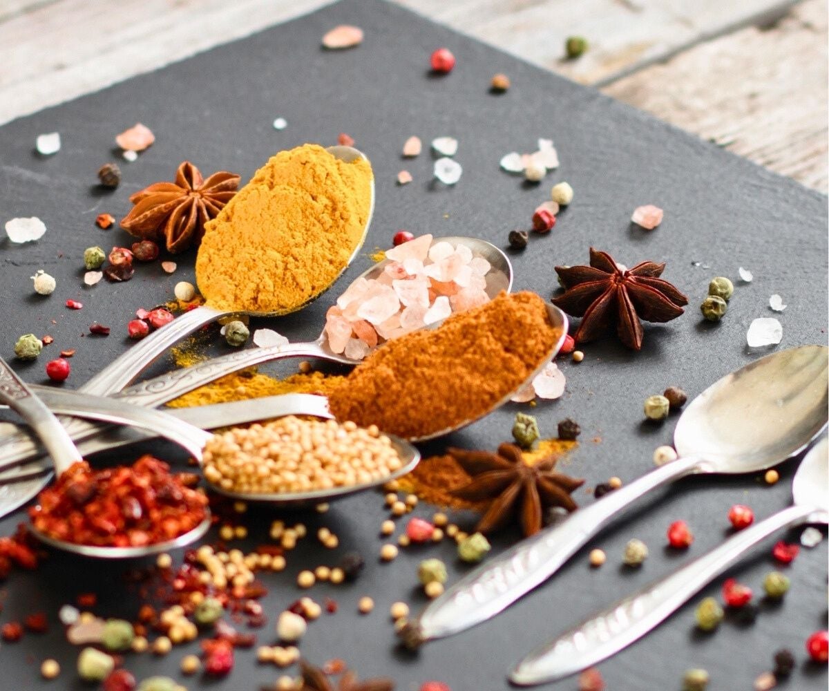 several spoons filled with a different spice each on a table for creating spice mixtures