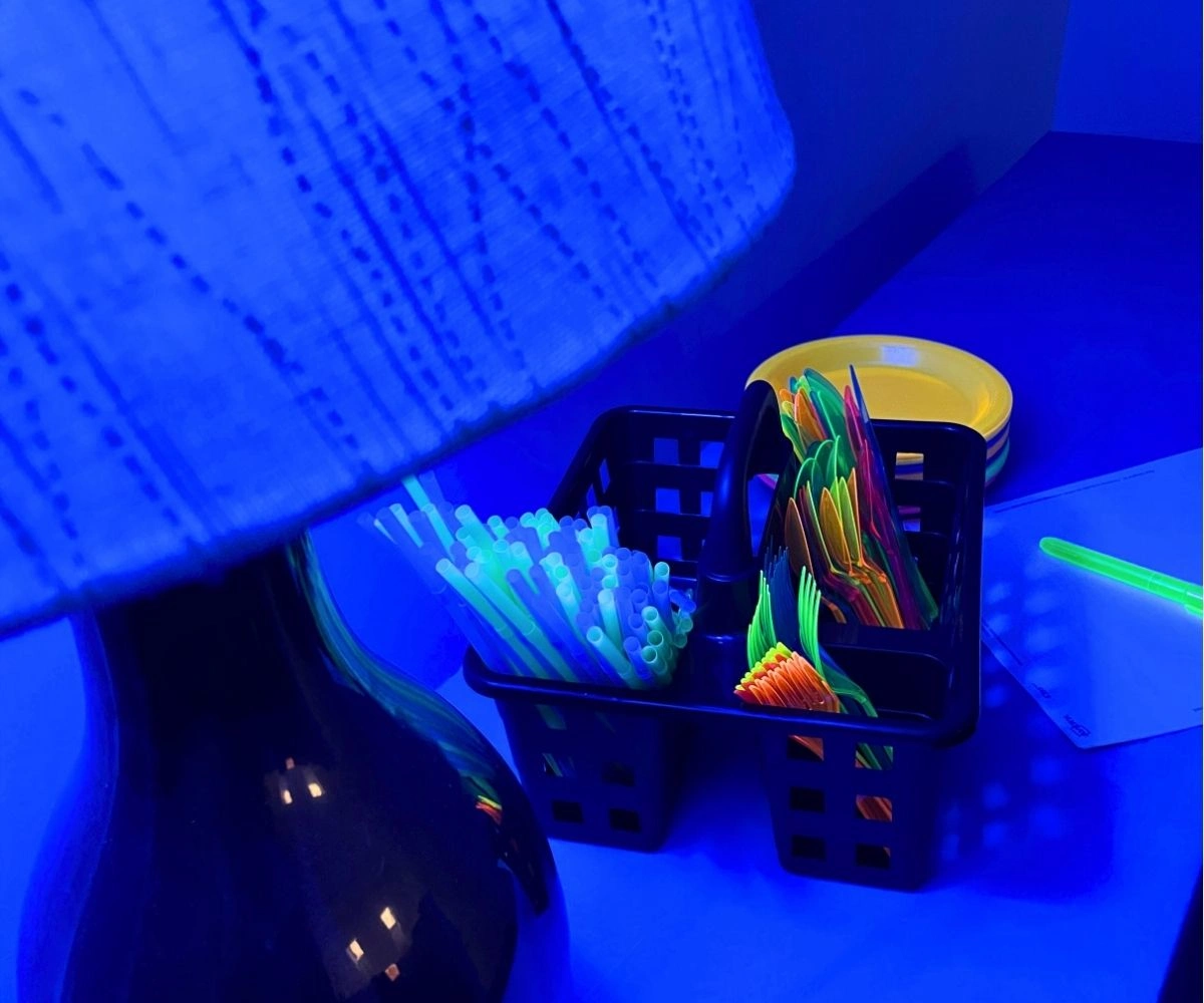 black lightbulb on with fluorescent plates, cutlery, and bracelets