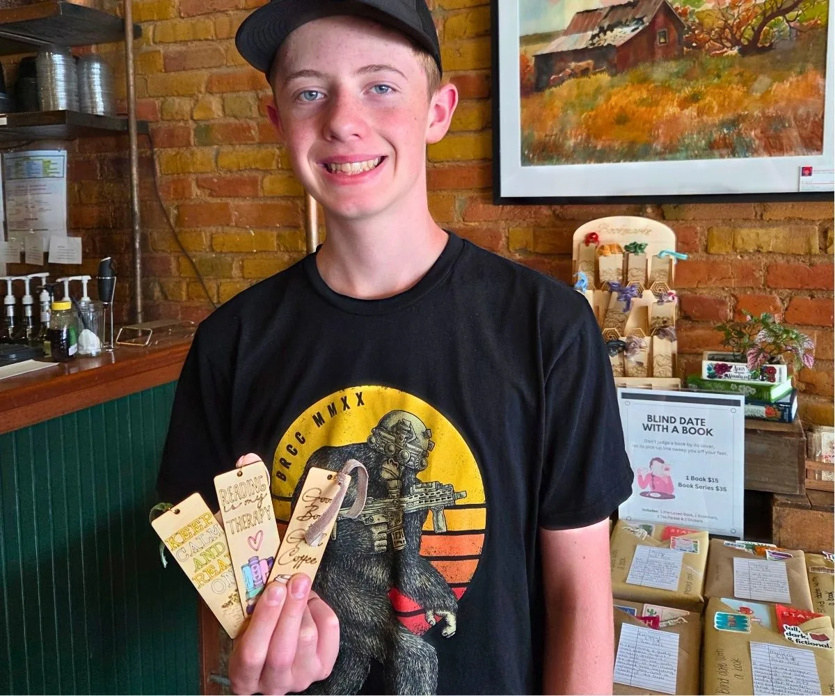 Teen Asher holding up his CO2 laser designs at a store location