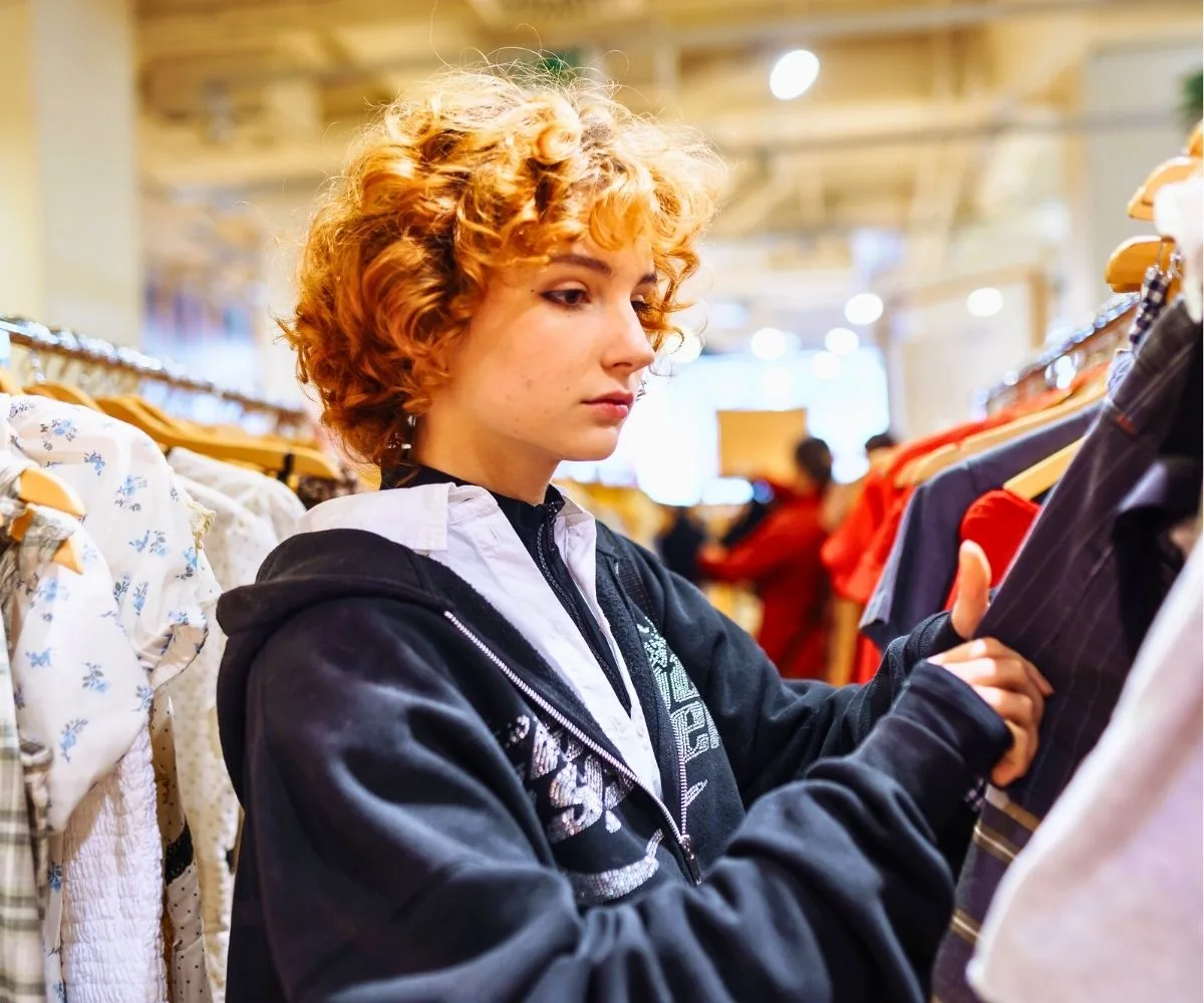 teen girl looking through vintage clothing to resell for cash
