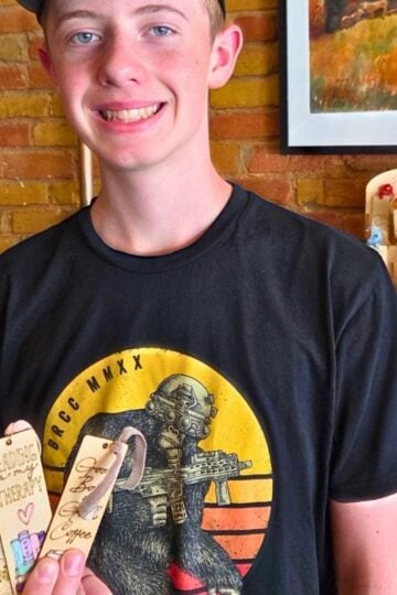 teen boy with handmade CO2 laser bookmarks at a shop