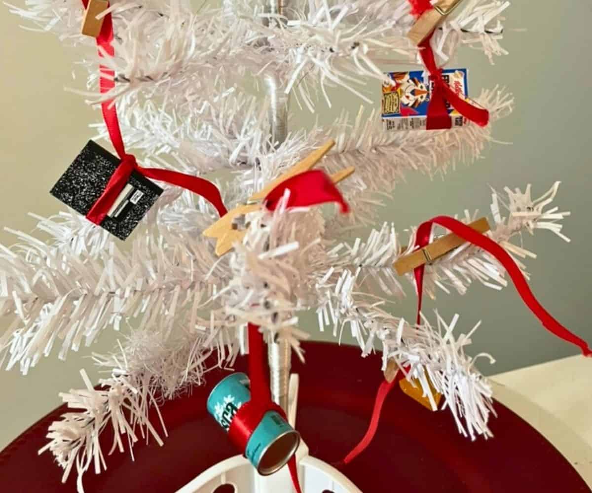 close up of the mini white Christmas tree with mini brands dangling by red ribbon throughout