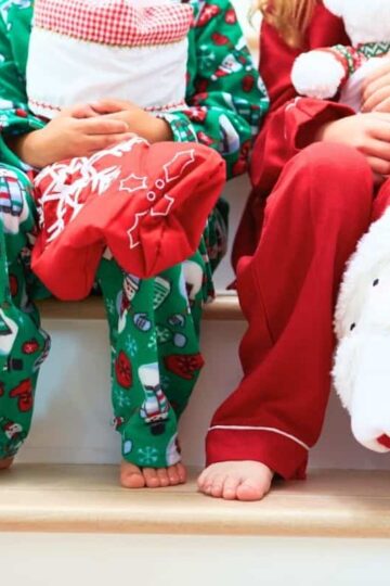 two kids in Christmas pajamas on stairs