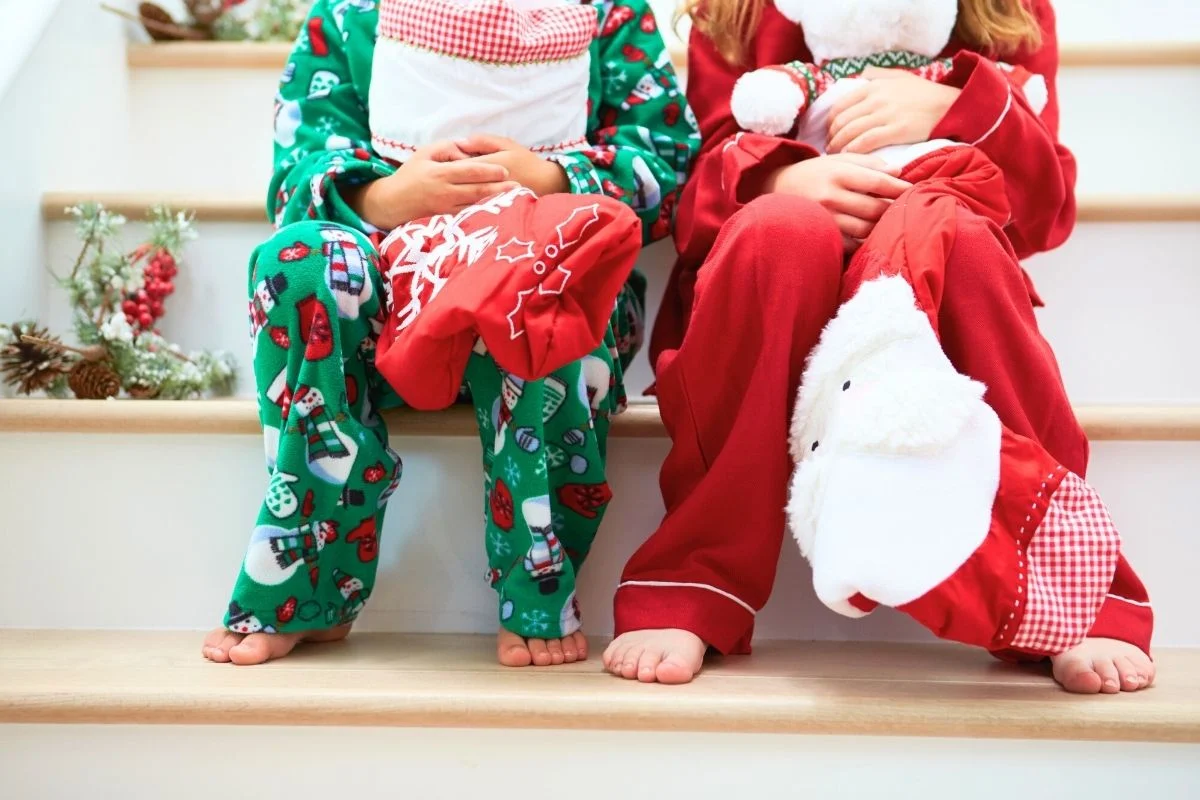 two kids in Christmas pajamas on stairs