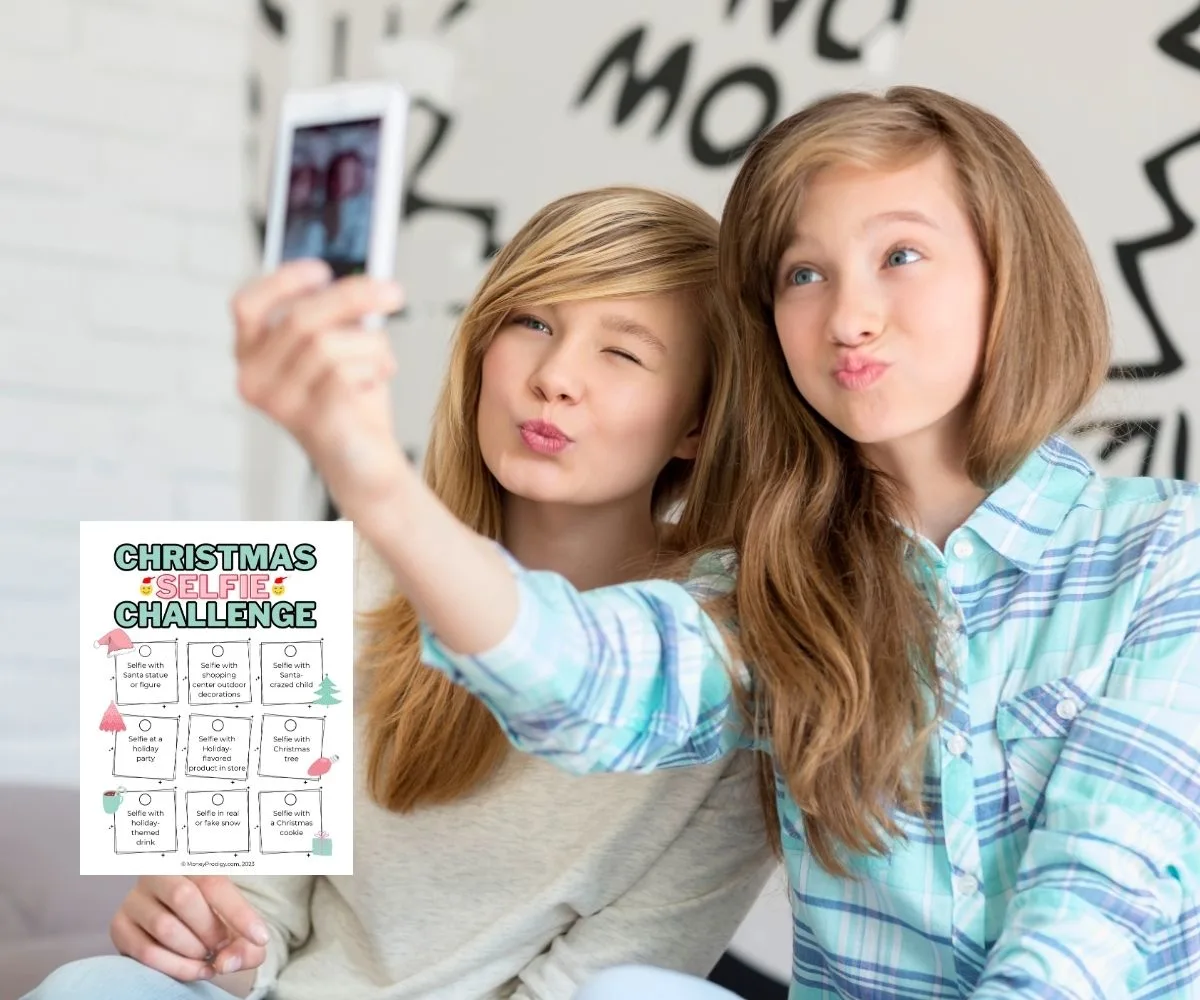 two teen girls taking a selfie with a PDF of the Christmas selfie challenge
