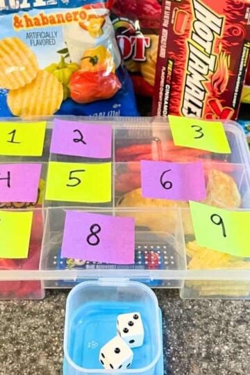 tacklebox with colored and numbered post its on outside, in front of dice and lots of extreme flavored snacks