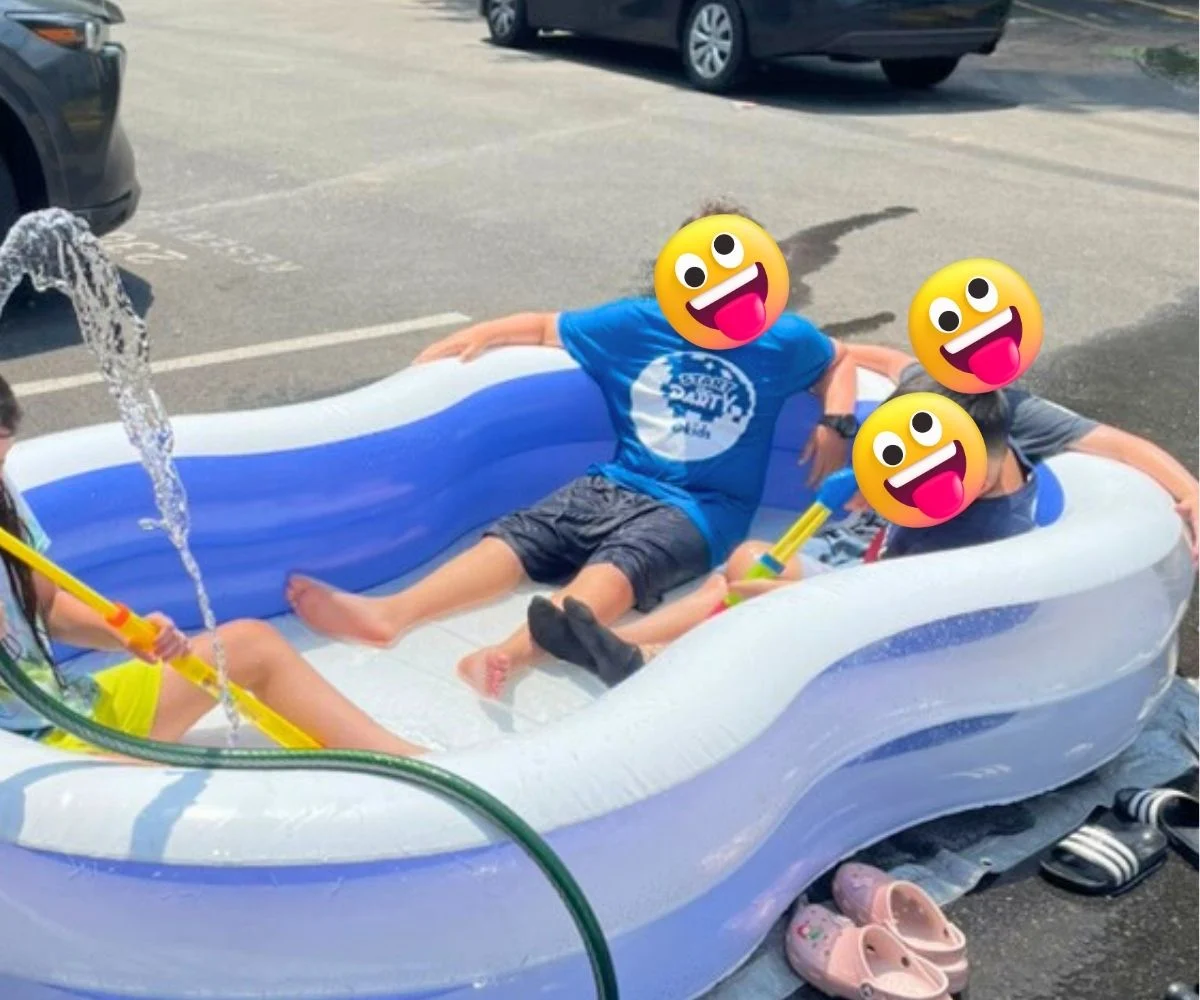 four kids in a large inflatable pool with smiley emojis over their faces