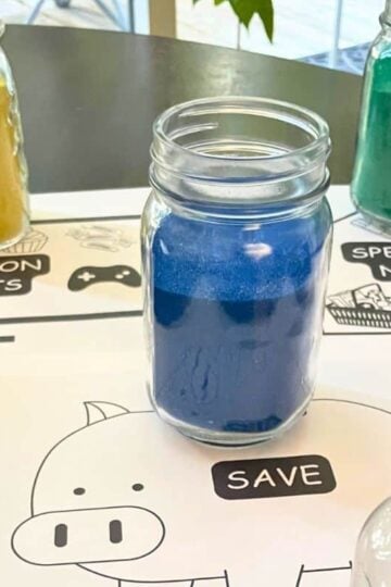three colored sand jars representing needs, wants, and saving money