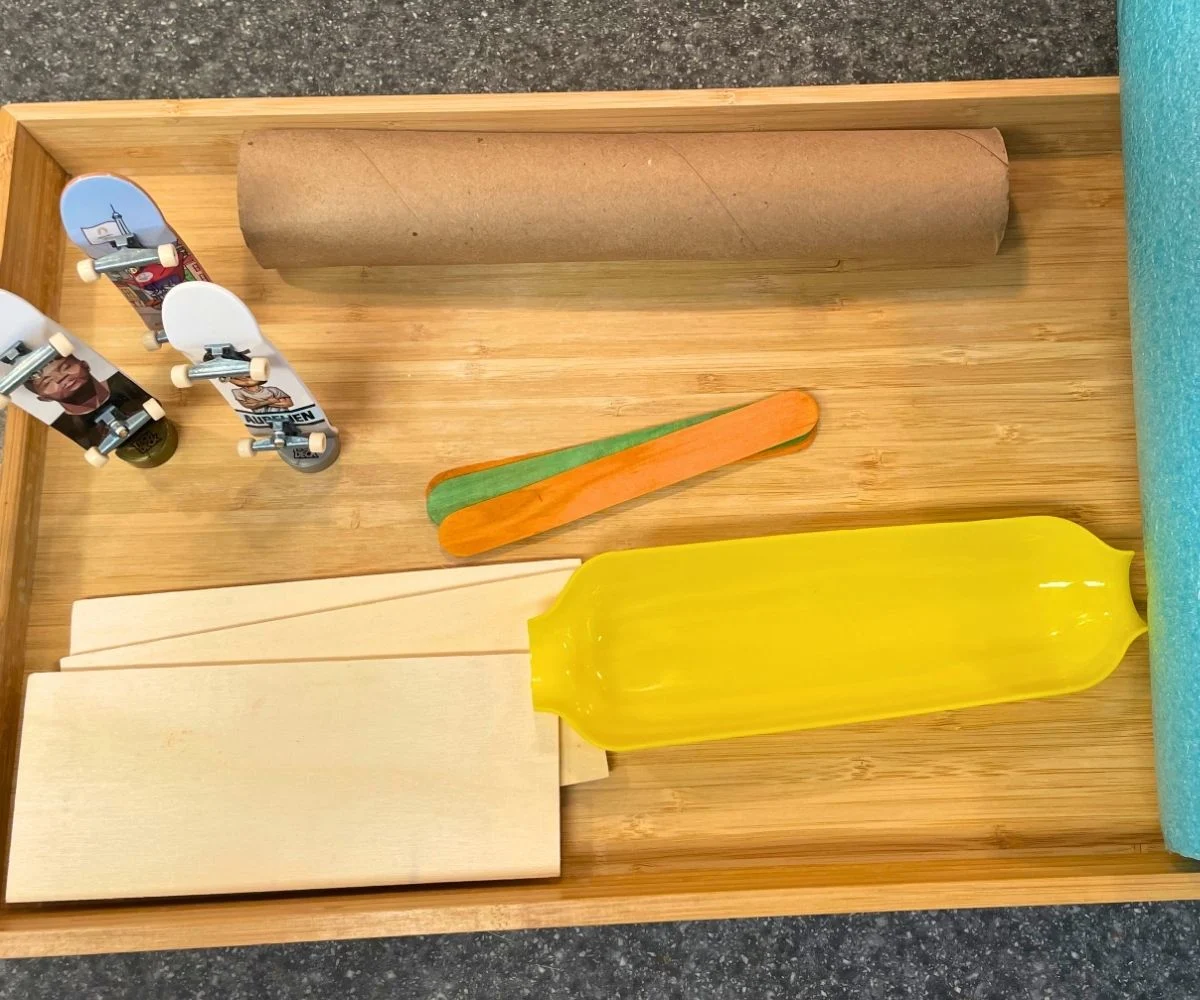 light wooden tray filled with household items and three tech decks standing up