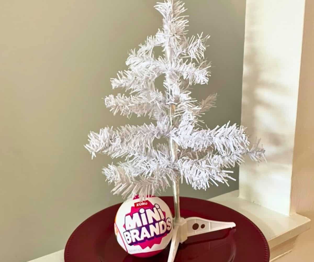 undecorated white mini tree on red charger plate with mini-brands package