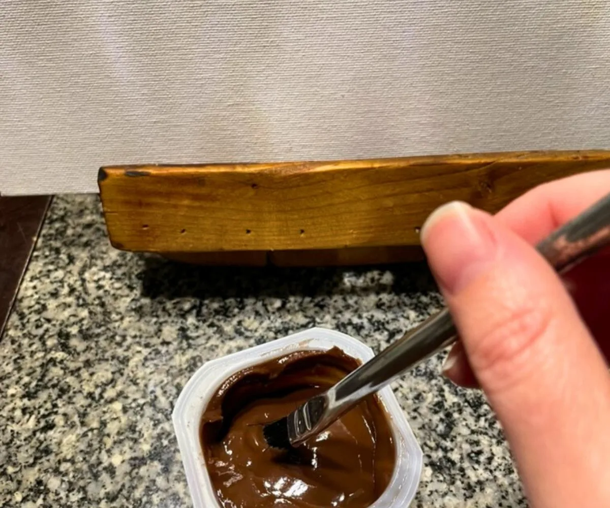 kid dipping paintbrush into chocolate pudding cup