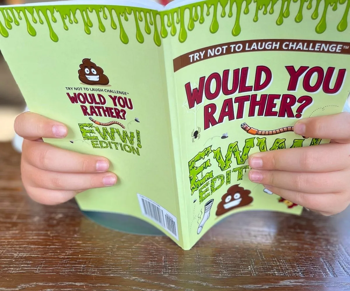child holding open a "Would You Rather Ewww Edition" book