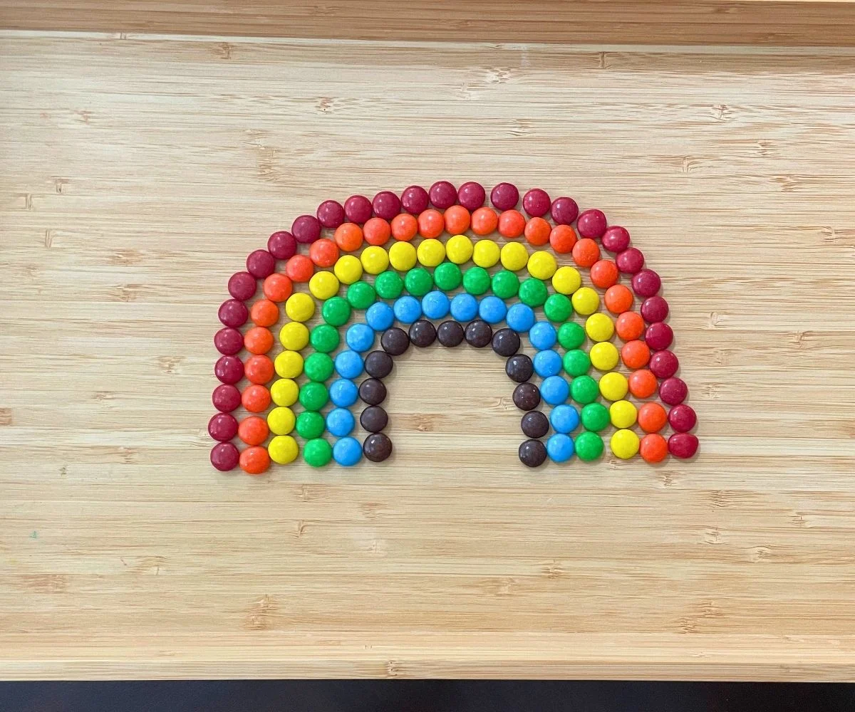 light wooden tray with rainbow M&M art