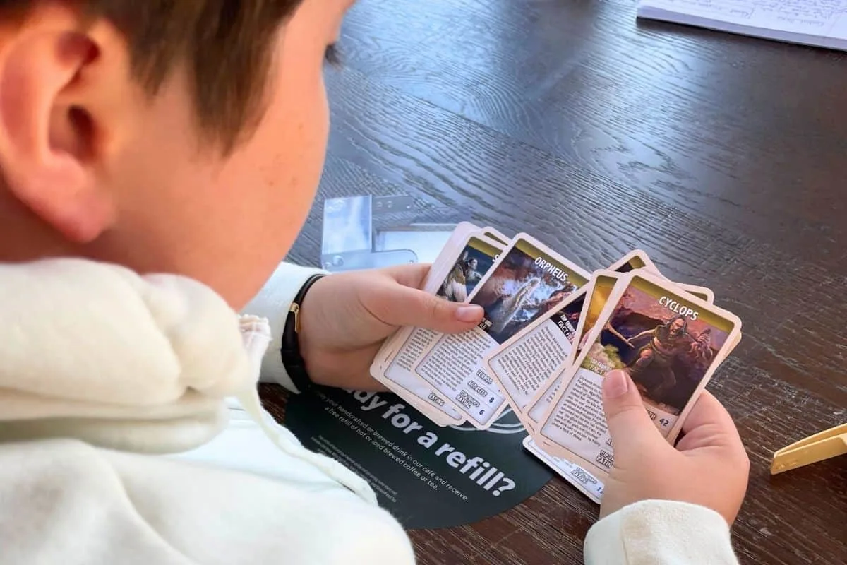 9 year old boy holding Top Trumps greek mythology cards
