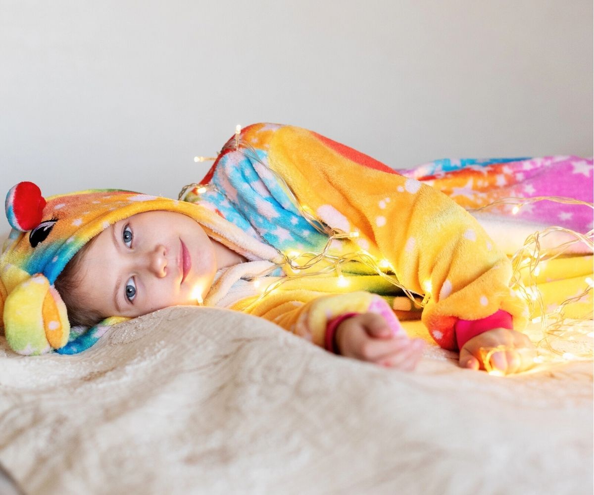 preteen girl wearing unicorn kigurumi and laying on a bed