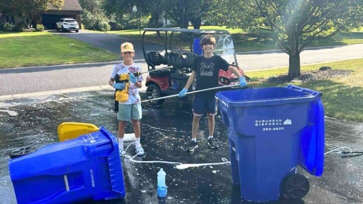 Splash Brothers outside with cleaning supplies next to two blue garbage cans they've cleaned