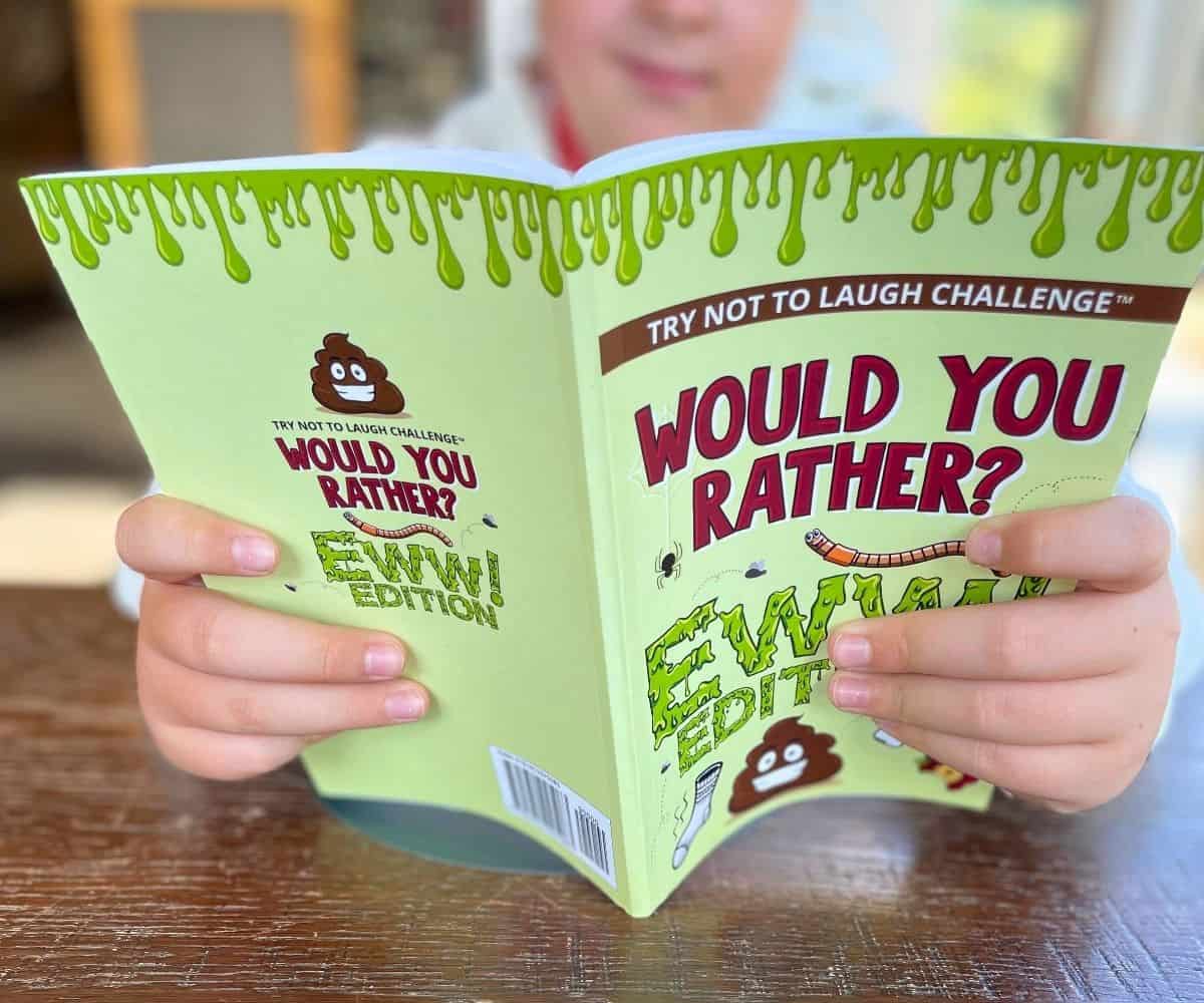 Preteen boy holding Would You Rather Ewwww Edition Book