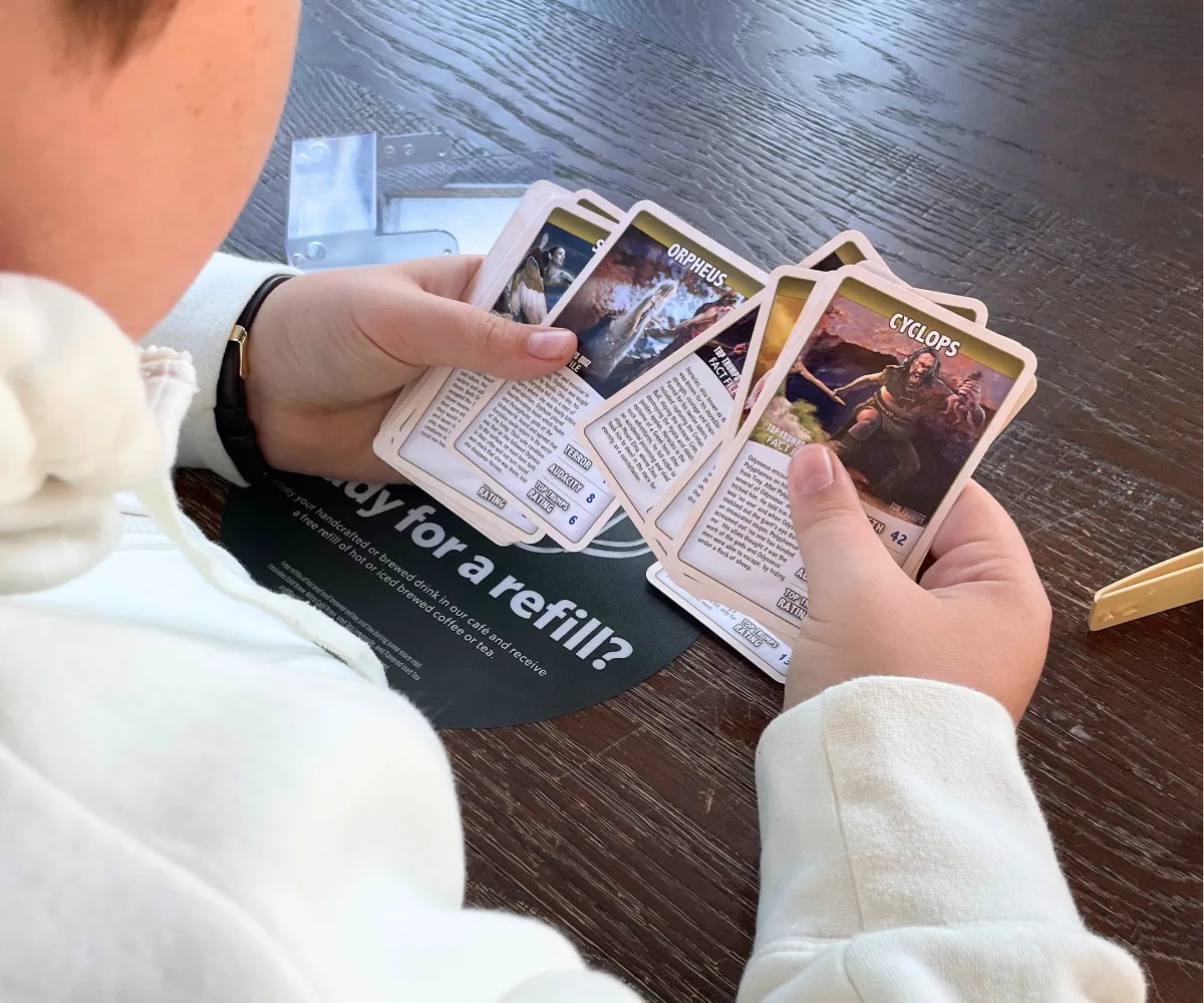 tween boy holding set of Top Trumps greek mythology cards to play
