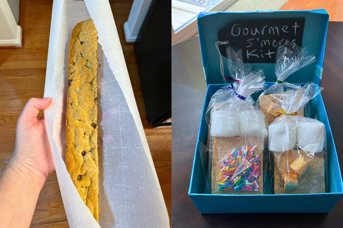 blue box with prepackaged gourmet s'mores kits in it, and a foot long cookie bar in someone's hand