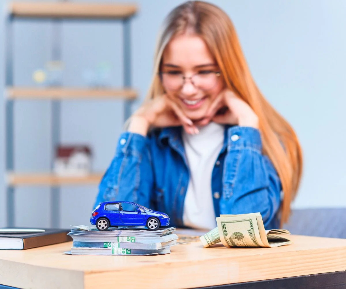 Teen girl with toy car and pile of money