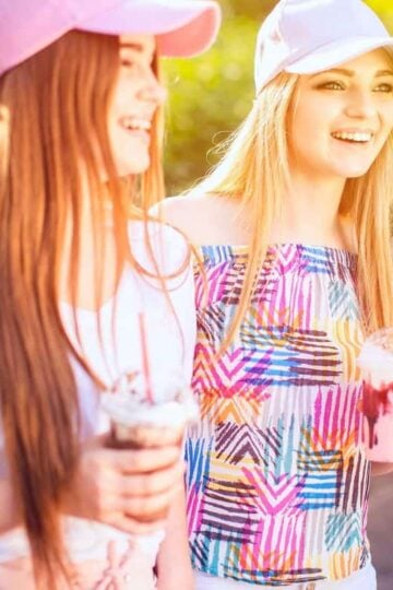 two teen girls in colorful shirts with manicured nails and colorful drinks