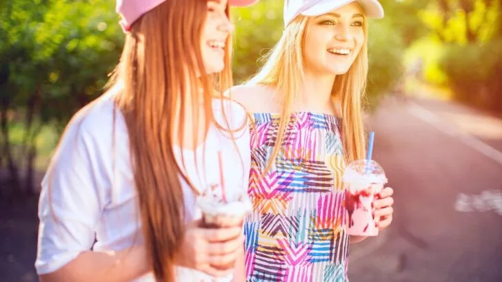 two teen girls in colorful shirts with manicured nails and colorful drinks