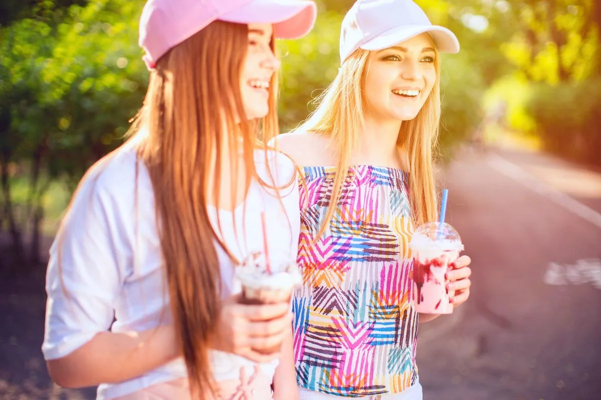 two teen girls in colorful shirts with manicured nails and colorful drinks