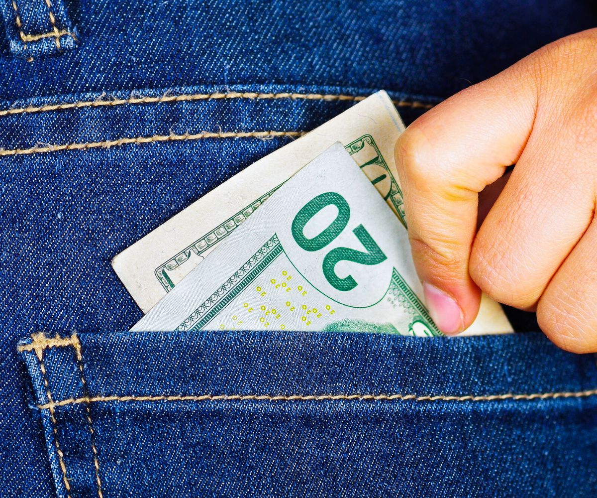 teen hand putting $20 into jean pocket