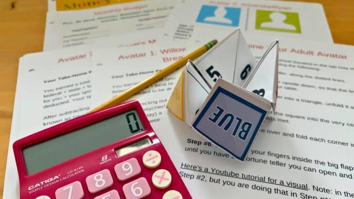 printed out fortune teller and money game on light wooden table with pink calculator