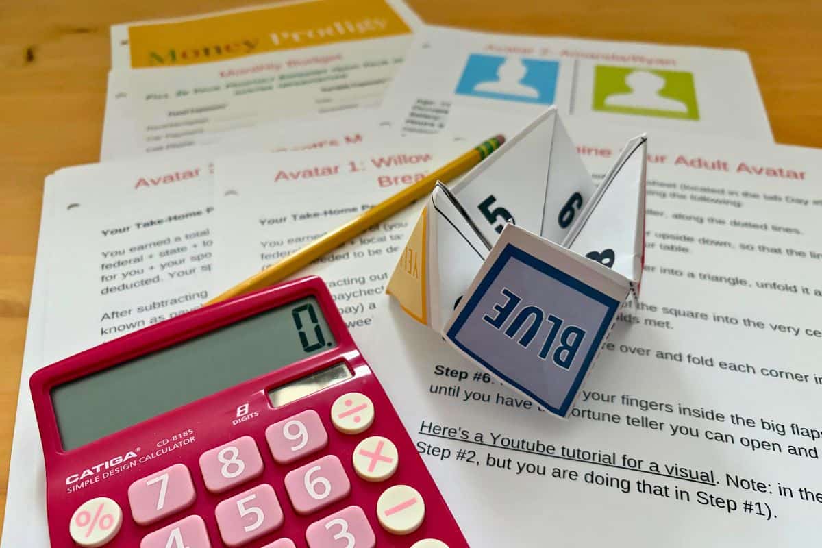 printed out fortune teller and money game on light wooden table with pink calculator